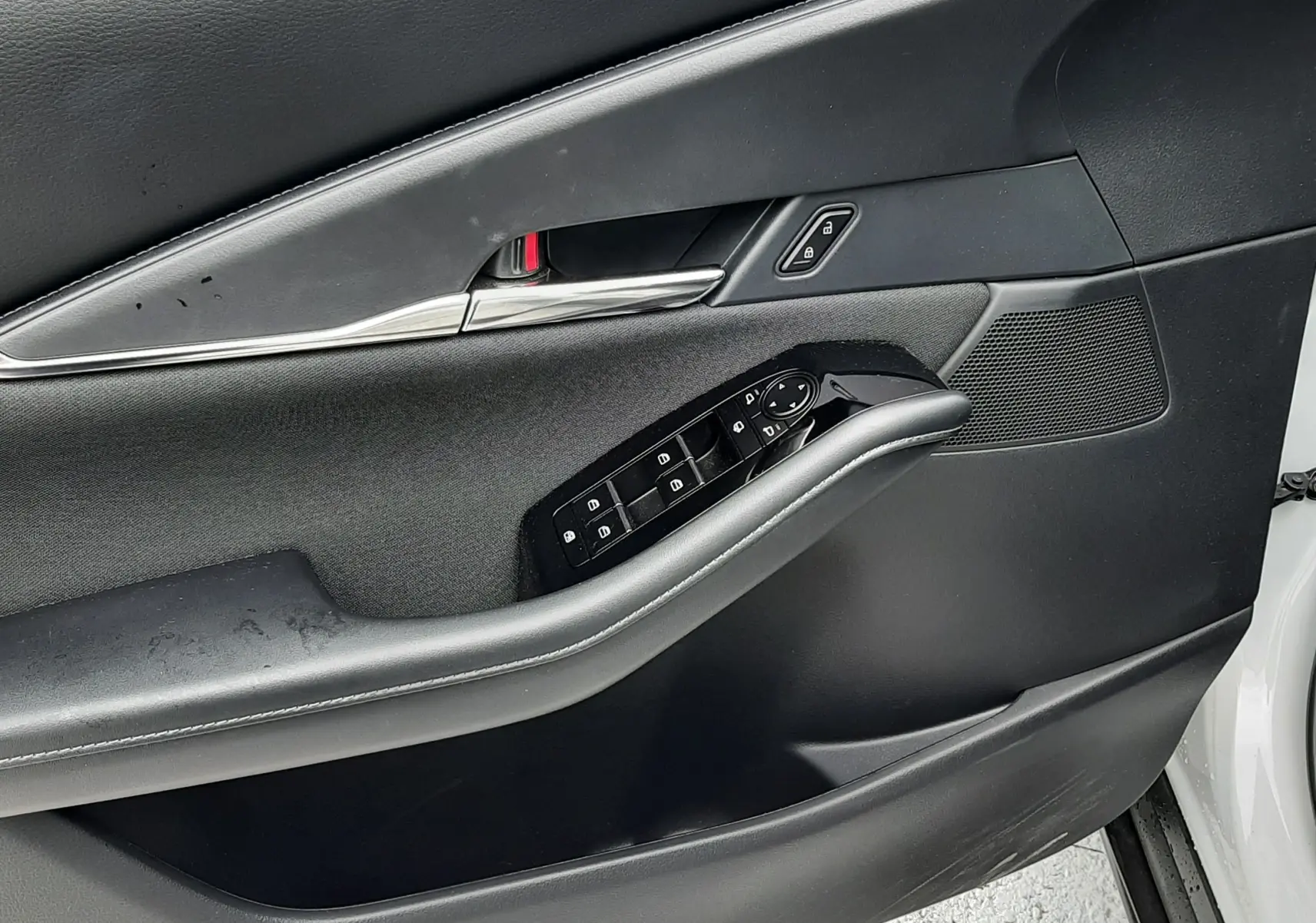 Vue rapprochée de la porte avant gauche noire du Mazda CX-30 2024 avec commandes électriques et poignée chromée.