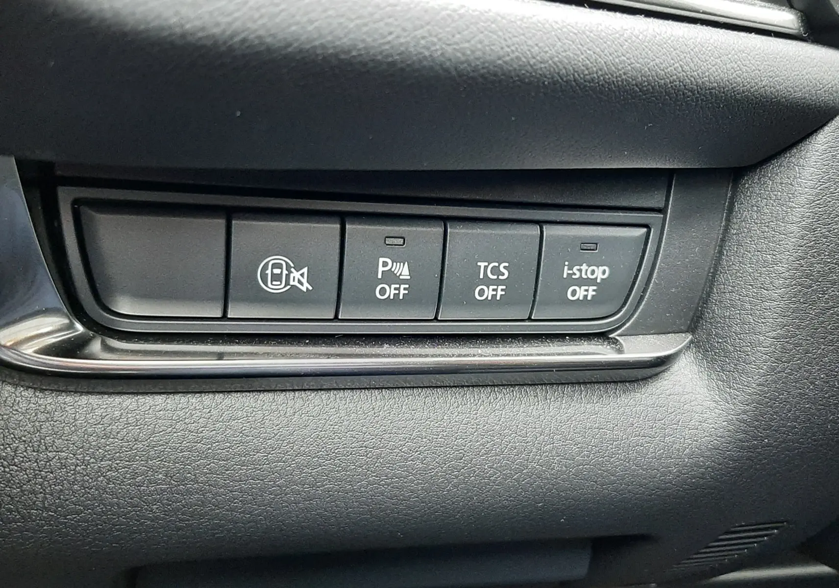 Gros plan sur les boutons de commande du tableau de bord noir du Mazda CX-30 2024 en Ceramic White, version Exclusive Line.