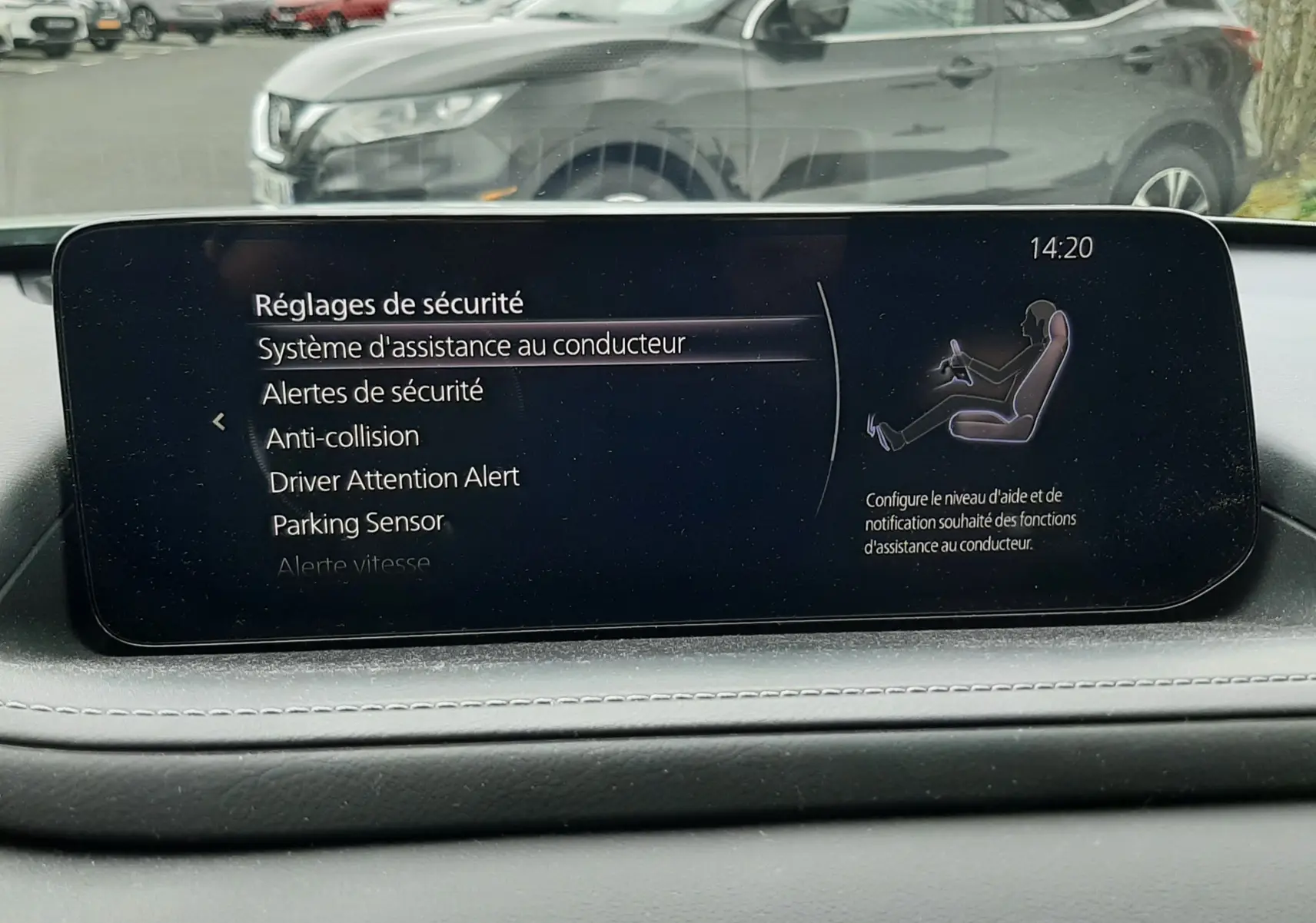 Vue avant d'un Mazda CX-30 blanc céramique garé, avec l'écran central du tableau de bord en premier plan.