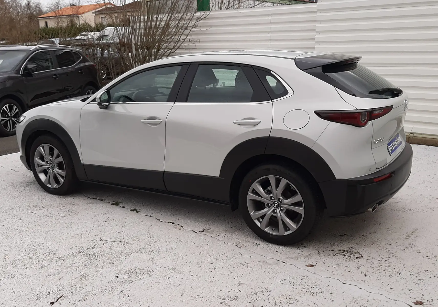 Vue 3/4 arrière droite d'un Mazda CX-30 2024 blanc céramique avec jantes alliage et détails noirs contrastants.