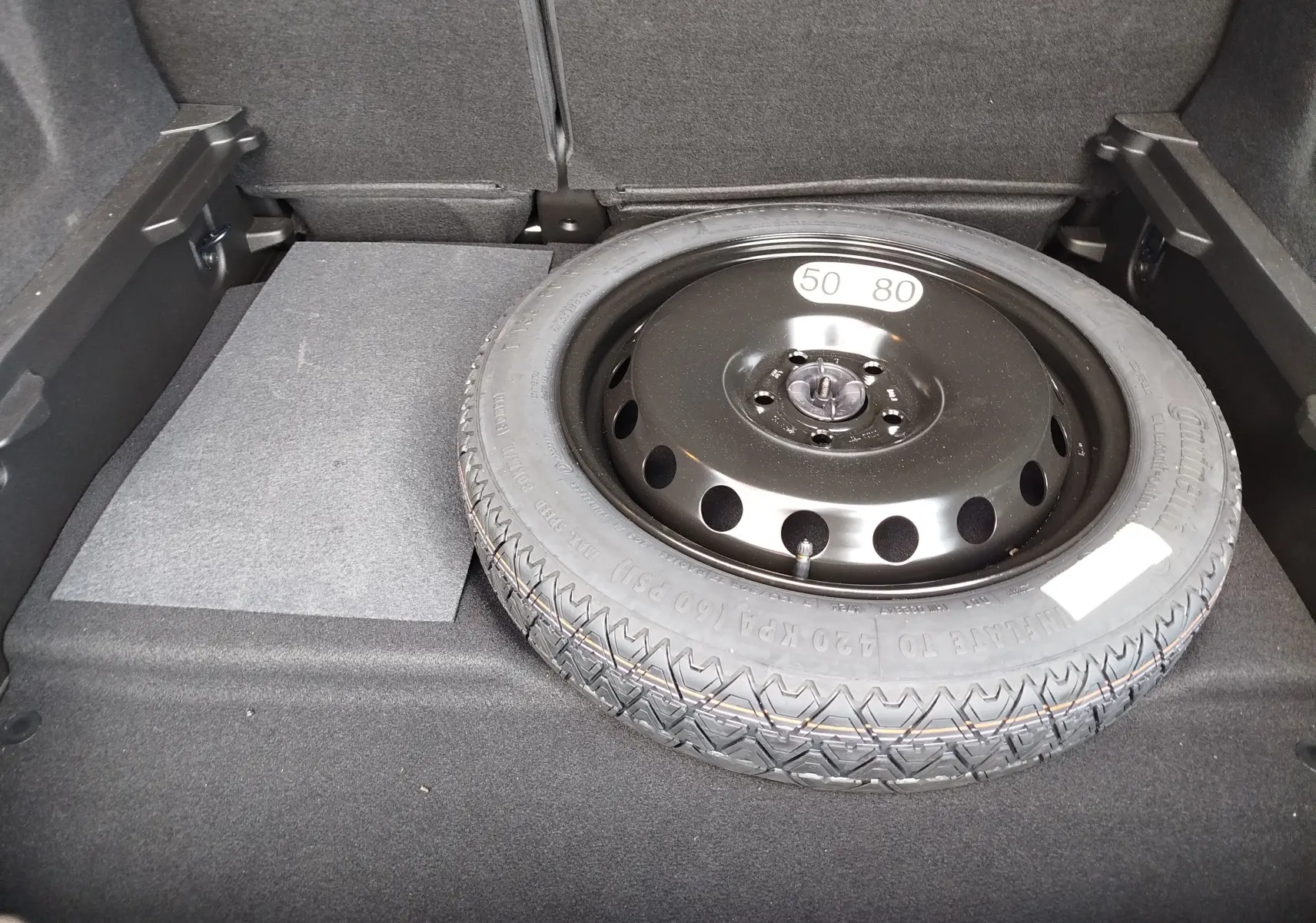 Vue rapprochée du coffre du Renault Symbioz 2025 montrant la roue de secours noire posée sur le tapis gris.