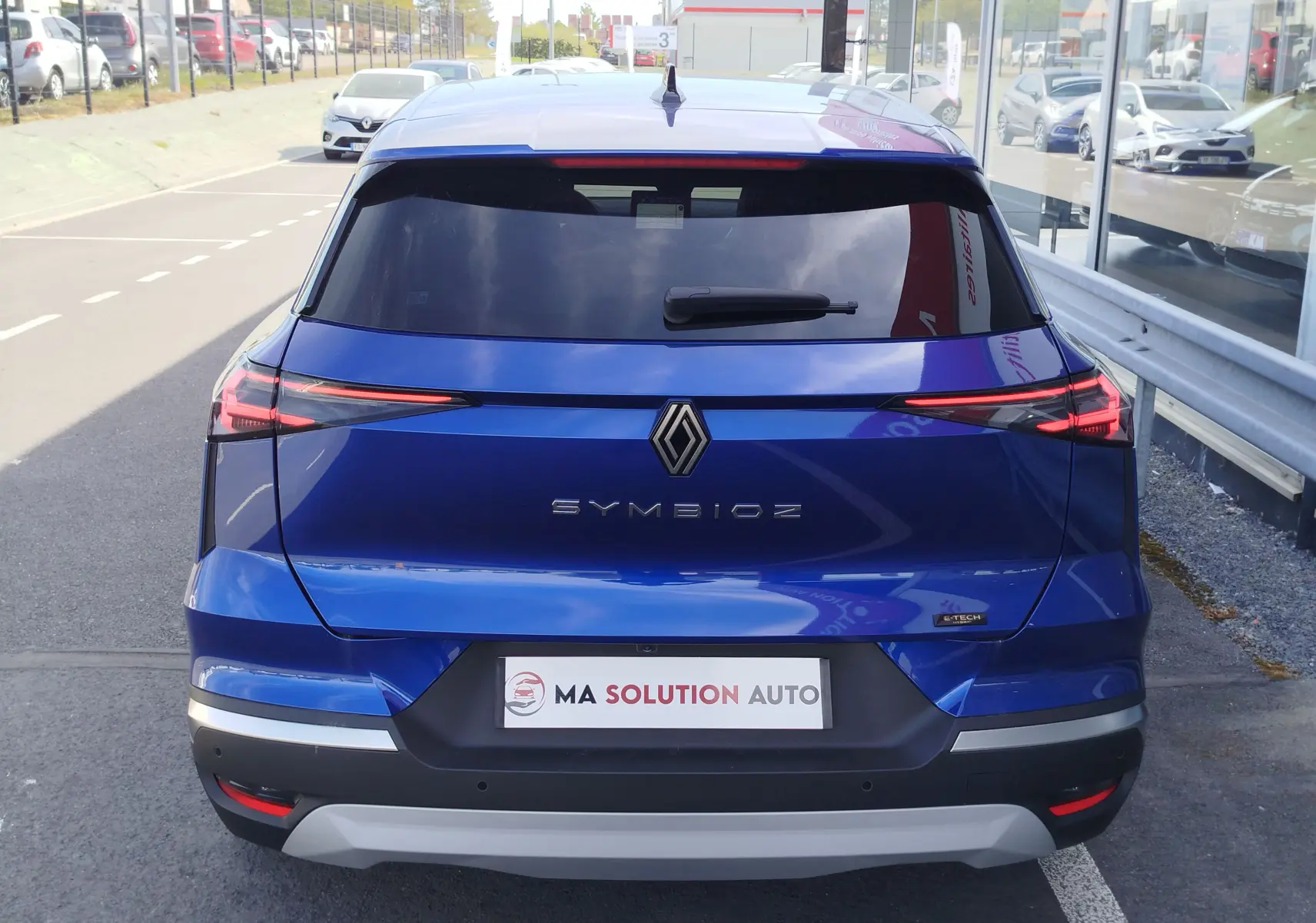 Vue arrière d’un Renault Symbioz bleu iron metal avec feux LED fins et logo central bien visible.