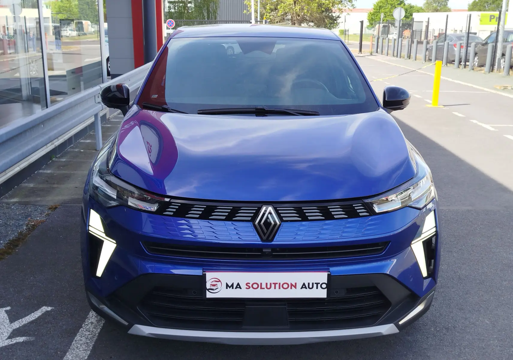 Vue frontale d'une Renault Symbioz 2025 bleu iron metal avec feux LED en forme de V et calandre moderne.