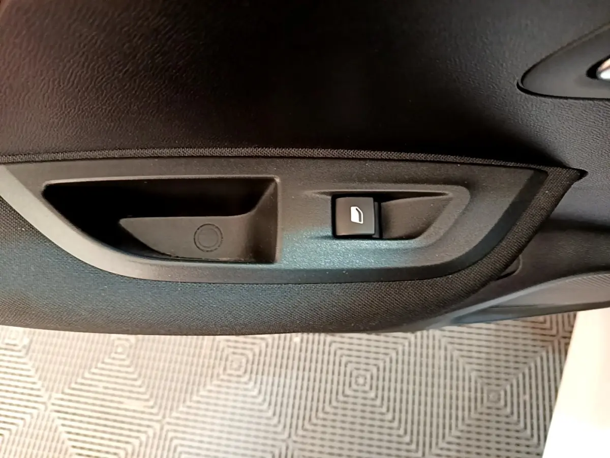 Gros plan sur la commande d'ouverture de trappe à carburant noire à l'intérieur d'une Peugeot 2008 blanche.