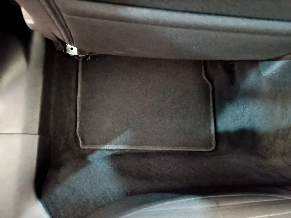 Vue rapprochée du tapis de sol noir côté passager avant du Peugeot 2008 blanc de 2021.