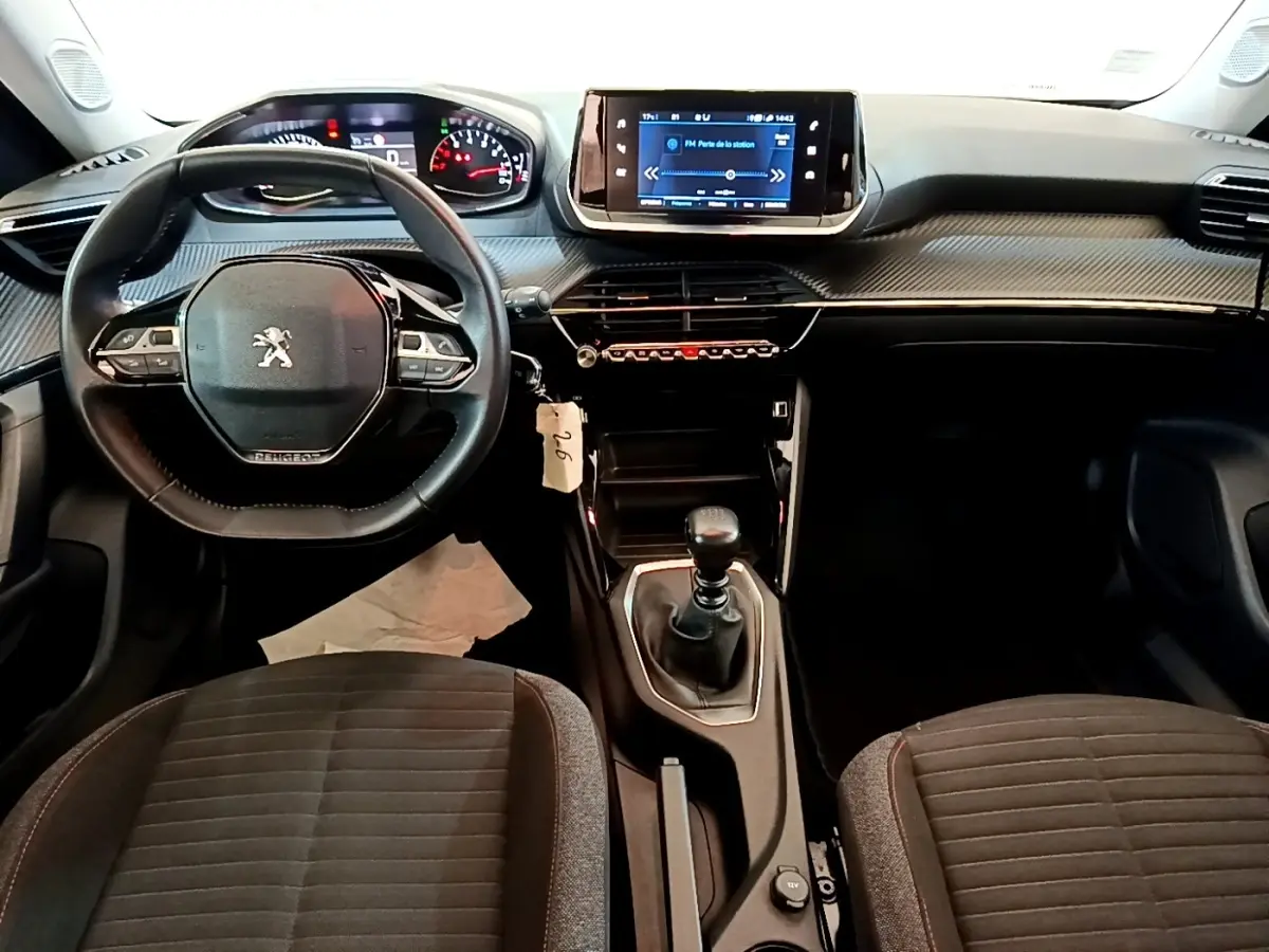 Vue intérieure du tableau de bord et volant cuir de la Peugeot 2008 1.5 BlueHDi, avec écran tactile central et boîte manuelle.