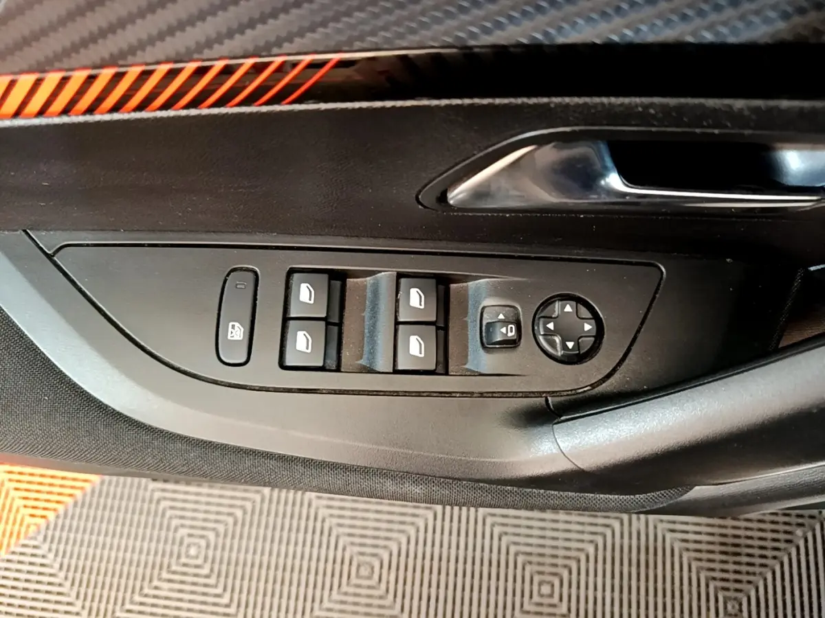 Vue rapprochée des commandes des vitres et rétroviseurs sur la portière côté conducteur d’un Peugeot 2008 blanc.