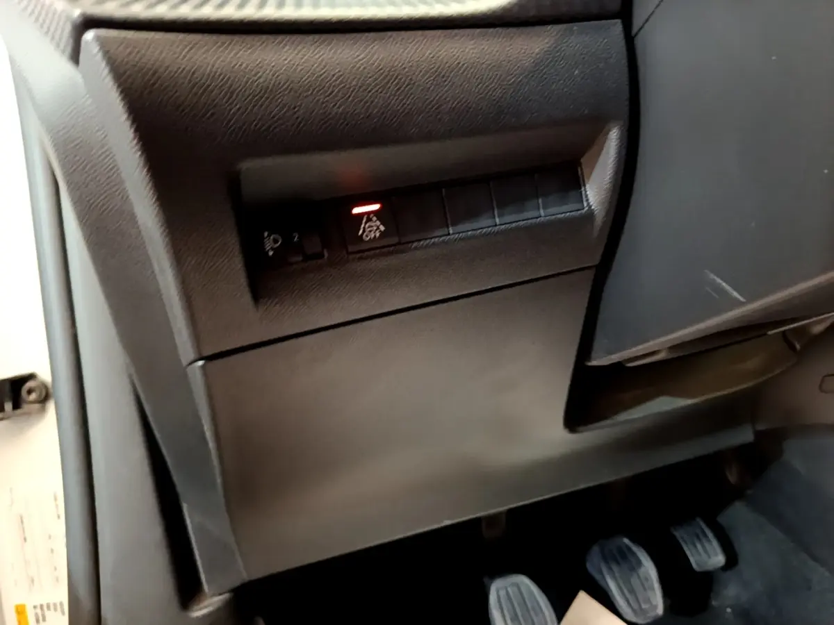 Vue intérieure sur la partie inférieure gauche du tableau de bord et pédalier du Peugeot 2008 blanc de 2021.