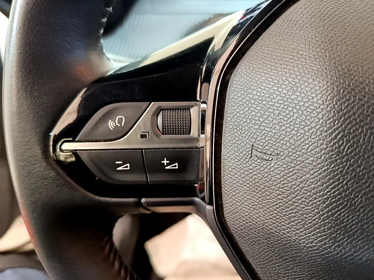 Gros plan sur les commandes gauche du volant cuir noir du Peugeot 2008 blanc, version 1.5 BlueHDi 2021.