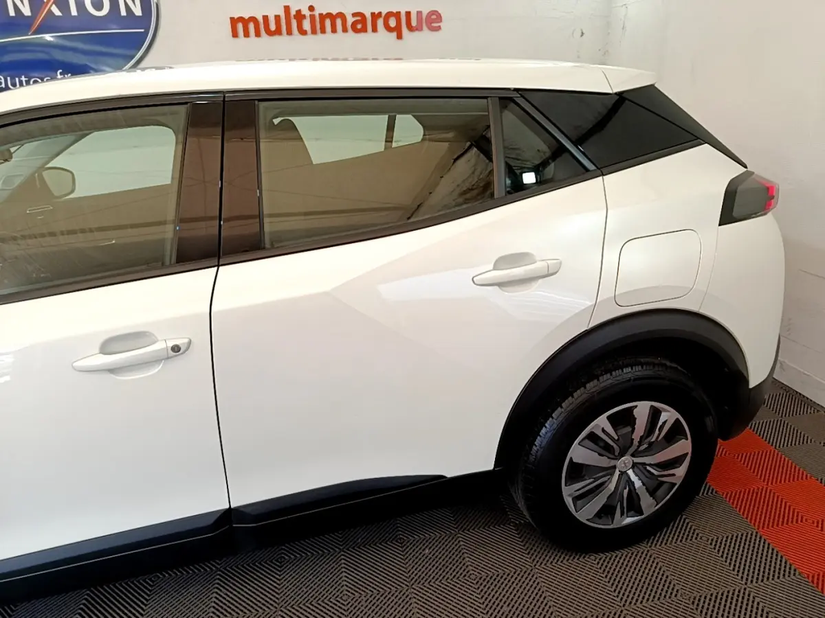 Vue latérale droite du Peugeot 2008 blanc 2021, mettant en valeur la porte arrière et la roue arrière avec jante stylisée.