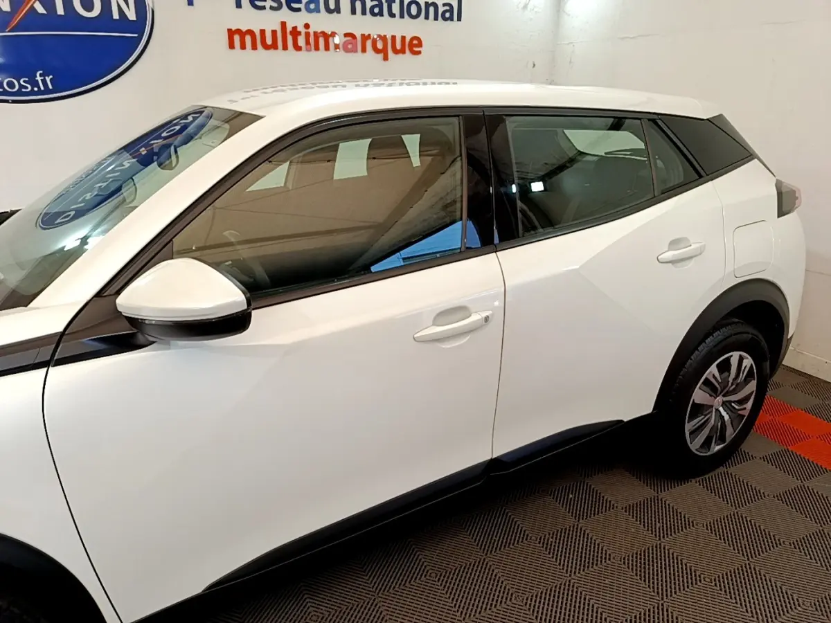 Profil côté gauche d’un Peugeot 2008 blanc, mettant en valeur les lignes anguleuses et les rétroviseurs blancs.