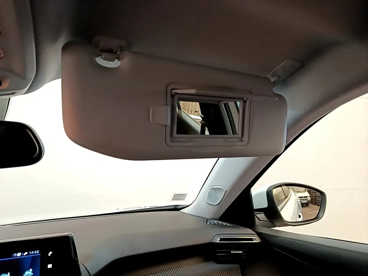 Vue intérieure côté passager du Peugeot 2008 blanc, avec pare-soleil déplié et miroir intégré visible.