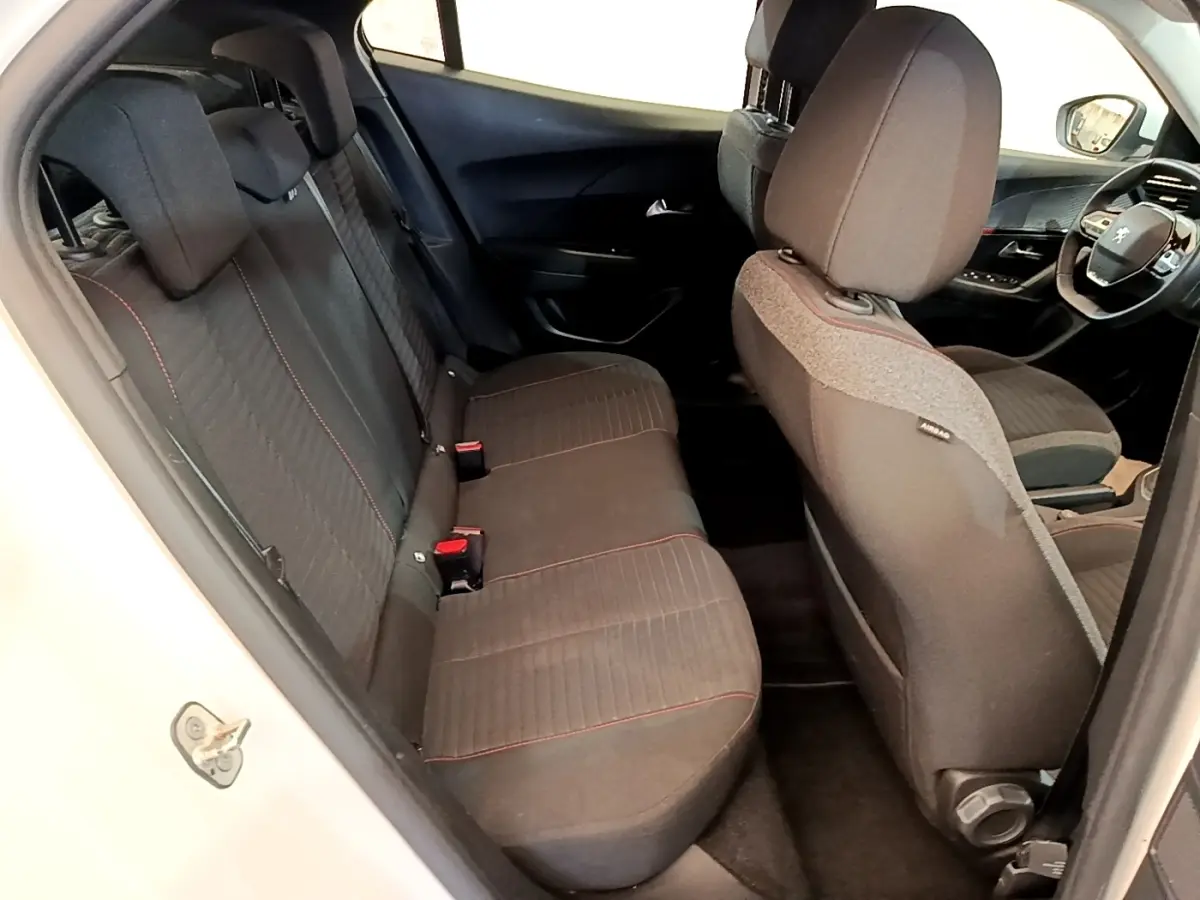 Vue intérieure côté gauche montrant les sièges arrière noirs avec surpiqûres rouges d’un Peugeot 2008 blanc.