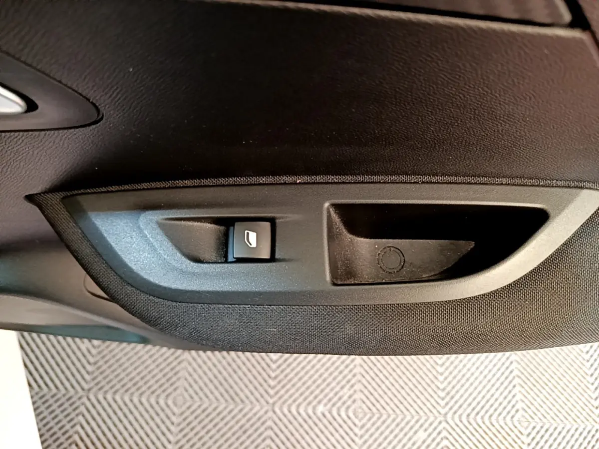 Gros plan sur le bouton de lève-vitre électrique côté porte intérieure d'une Peugeot 2008 blanche de 2021.
