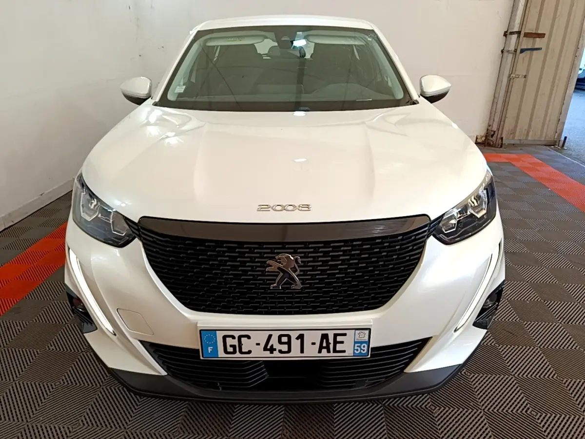 Vue avant d’un Peugeot 2008 blanc avec calandre noire et feux LED, immatriculé en France, dans un garage.