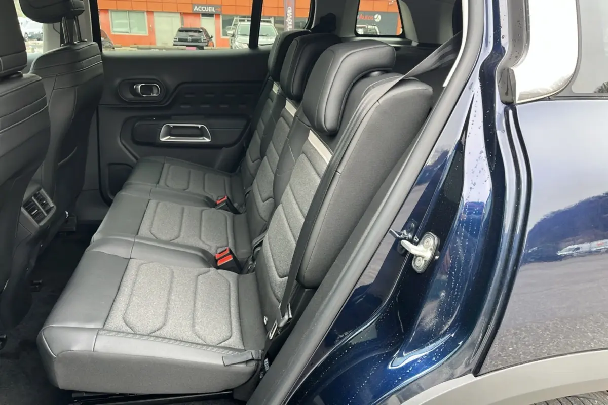 Vue latérale intérieure montrant les trois sièges arrière individuels en tissu gris du Citroën C5 Aircross Hybrid Eclipse Blue.