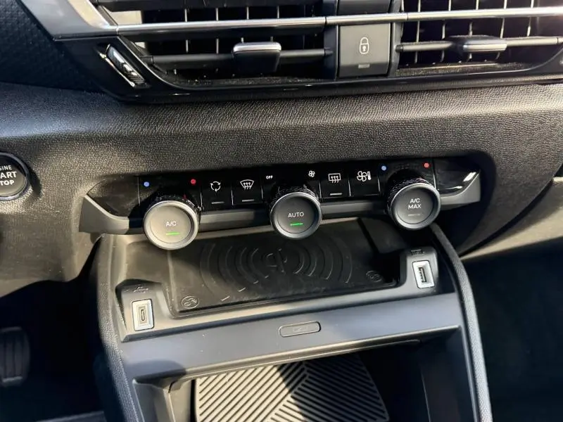 Détail du tableau de bord gris du Citroën C4 2024, montrant les commandes de climatisation et la zone de recharge sans fil.