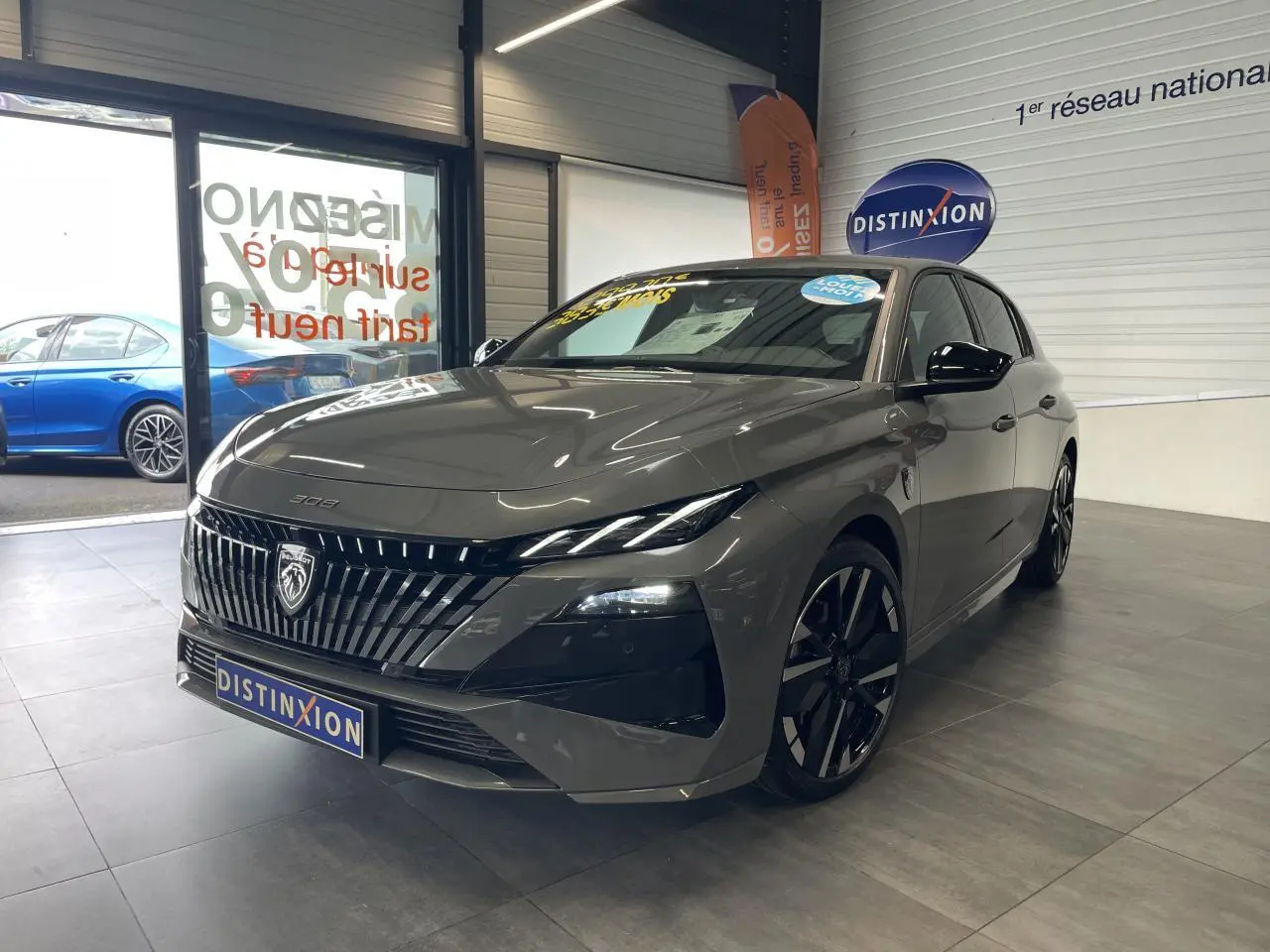 PEUGEOT 308 gris sélénium vue 3/4 avant en intérieur, calandre noire brillante et jantes alliage bi-ton.