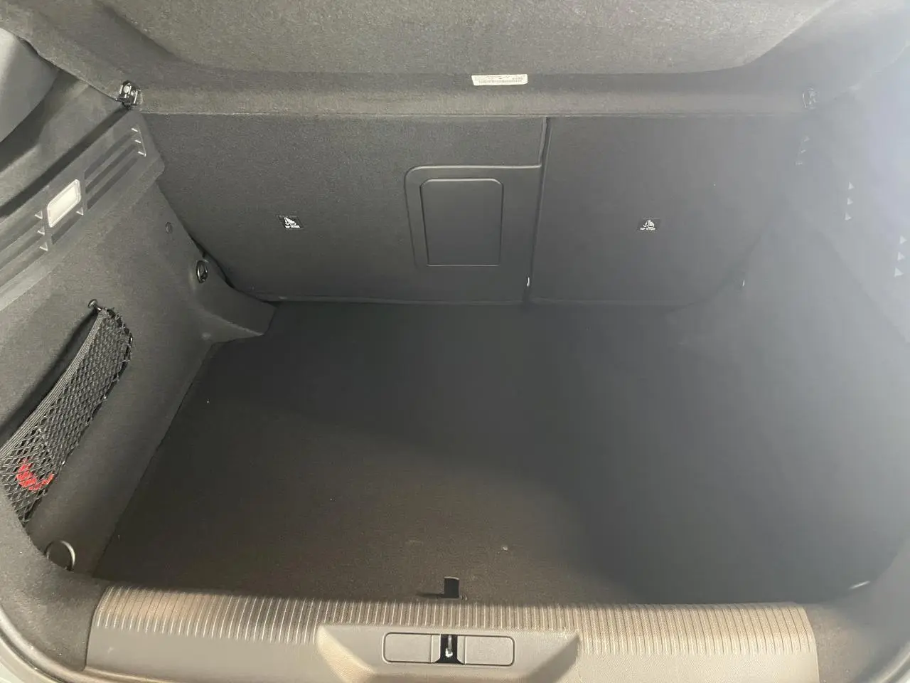 Vue intérieure du coffre spacieux et noir de la Peugeot 308 GT 2026 en gris Selenium, sans chargement visible.