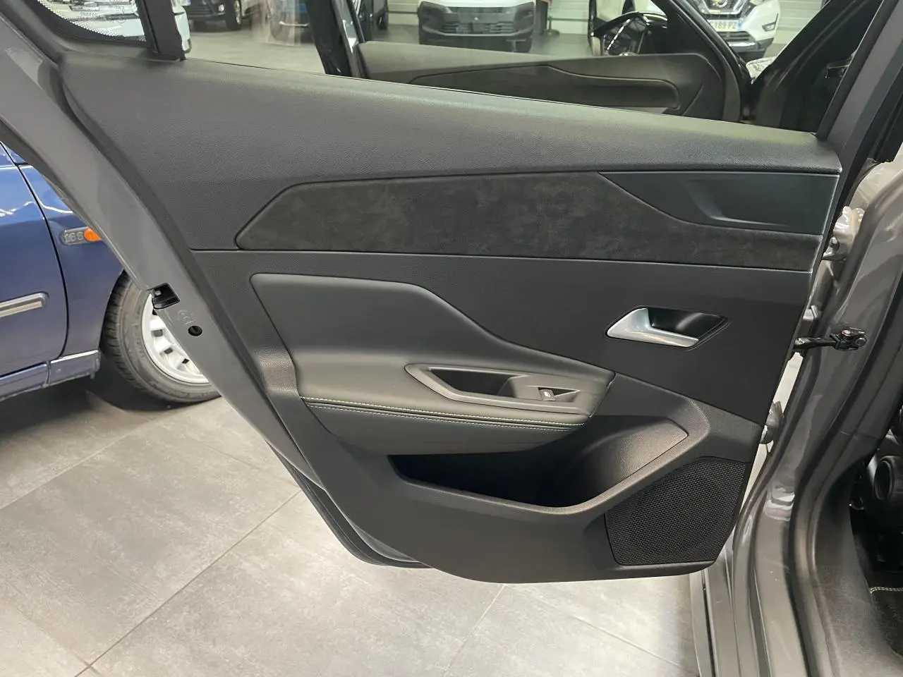 Vue intérieure de la porte arrière droite gris sélénium de la Peugeot 308 GT avec surpiqûres vert Adamite et haut-parleur intégré.