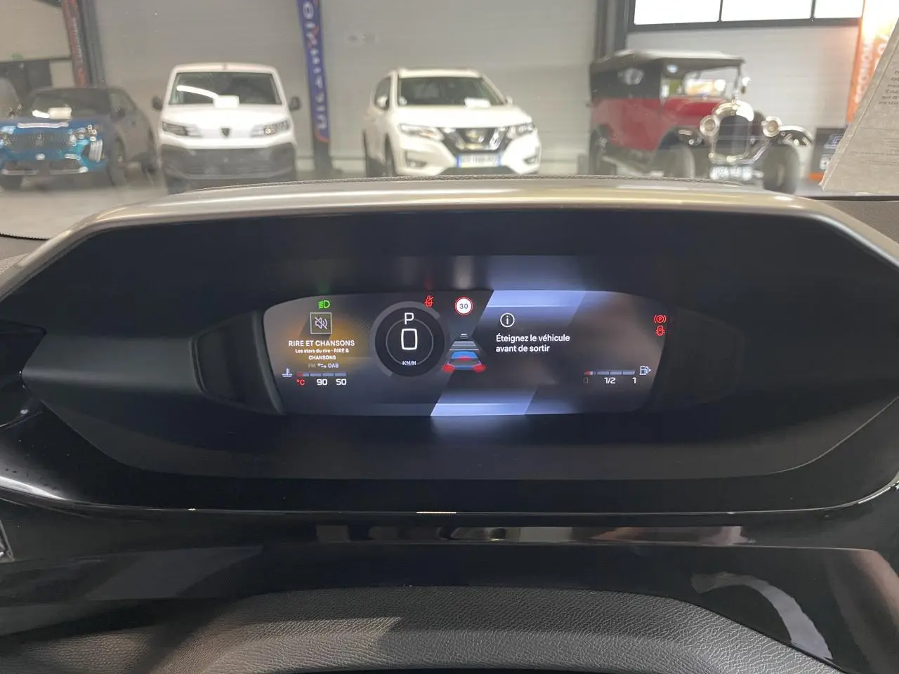 Vue du combiné numérique de la Peugeot 308 gris sélénium, affichant le mode parking et alertes sur fond noir.