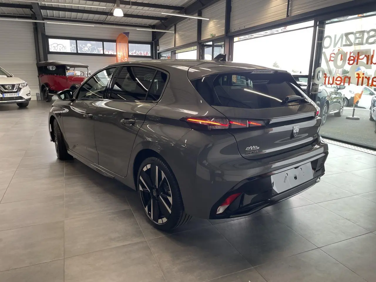 Vue 3/4 arrière droite d'une Peugeot 308 gris selenium avec feux arrière à LED et jantes alliage bi-tons.