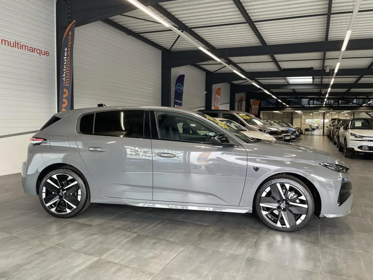 Peugeot 308 gris selenium vue de profil côté gauche en intérieur avec jantes alliage bi-tons et vitres teintées.
