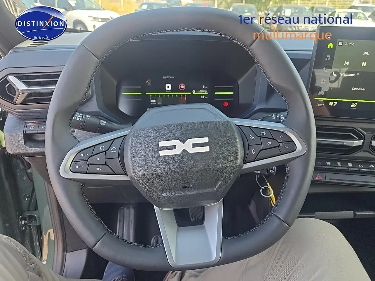 Vue intérieure centrée sur le volant multifonction du Dacia Duster vert kaki avec tableau de bord digital et écran tactile.