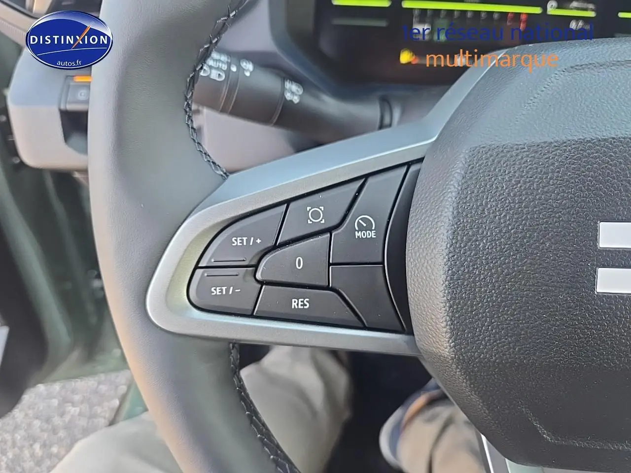 Gros plan sur les commandes multifonctions à gauche du volant du Dacia Duster vert kaki 2025, intérieur conducteur.