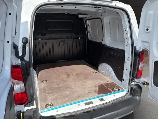 Vue arrière ouverte du Citroën Berlingo blanc 2025 montrant l'espace de chargement avec plancher bois et cloison pleine noire.