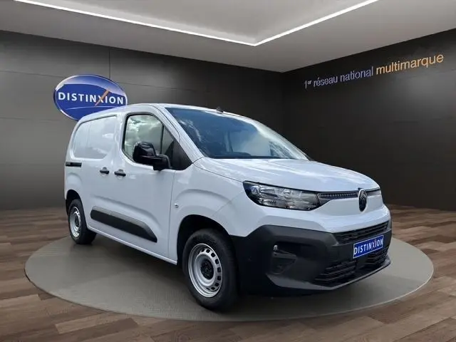 Vue 3/4 avant d’un utilitaire Citroën Berlingo blanc avec pare-chocs noir et jantes acier en showroom.