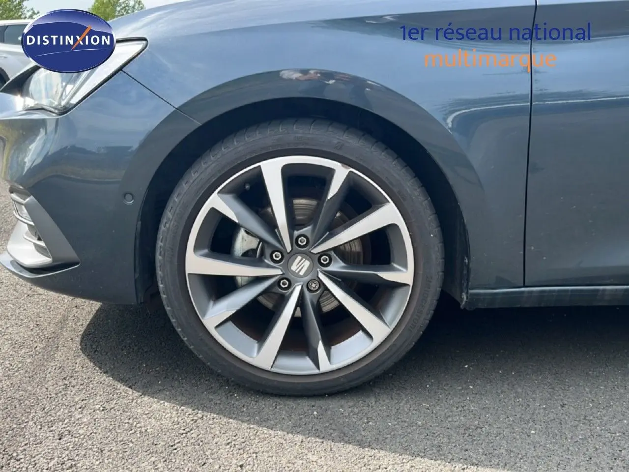 Gros plan sur la roue avant gauche d'une SEAT LEON ST 1.5 eTSI gris magnétique métal avec jante alliage distinctive.