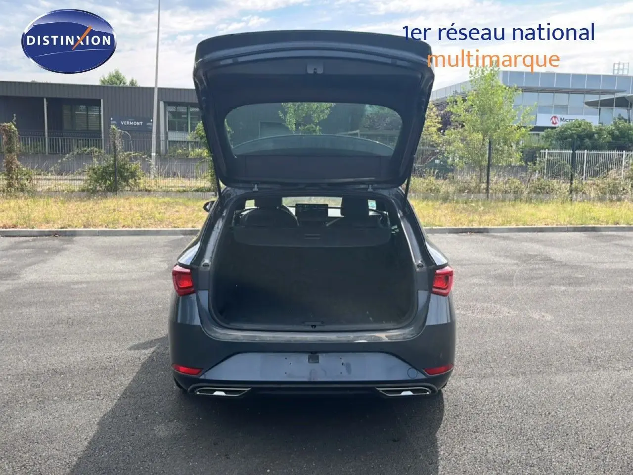 Vue arrière d'une SEAT LEON ST 1.5 eTSI 150CH FR Special Edition gris magnétique avec coffre ouvert sur parking.