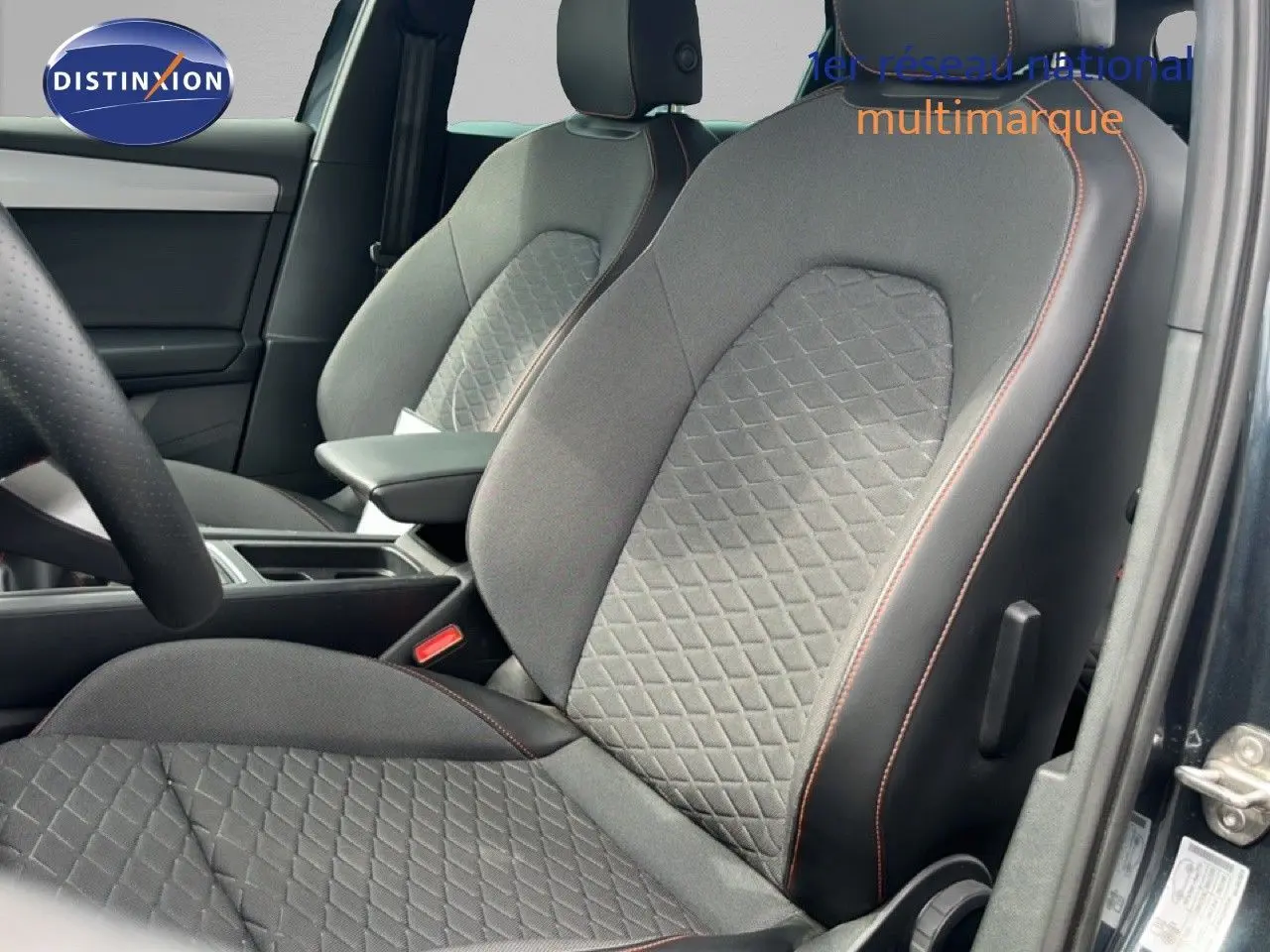 Vue intérieure côté conducteur du siège avant gris noir avec surpiqûres orange du SEAT LEON ST 1.5 eTSI 2025.