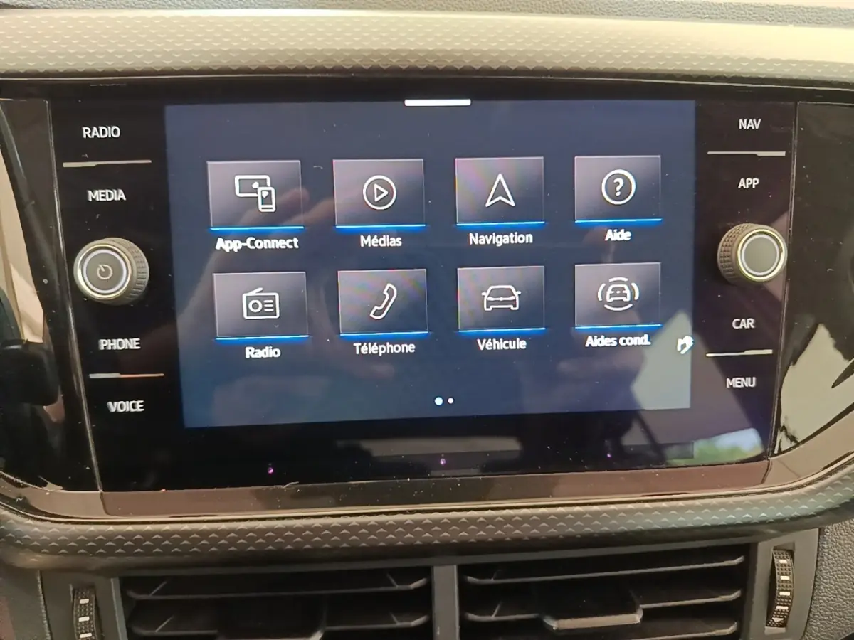Écran tactile central du tableau de bord du Volkswagen T-Cross blanc, affichant le menu principal multimédia.