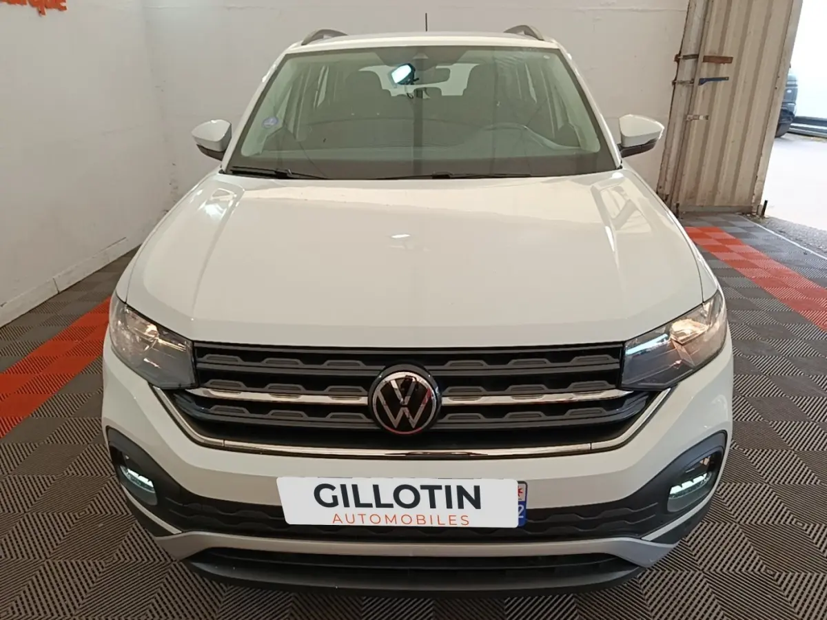 Vue avant d'un Volkswagen T-Cross blanc avec calandre noire et feux diurnes LED allumés en intérieur.