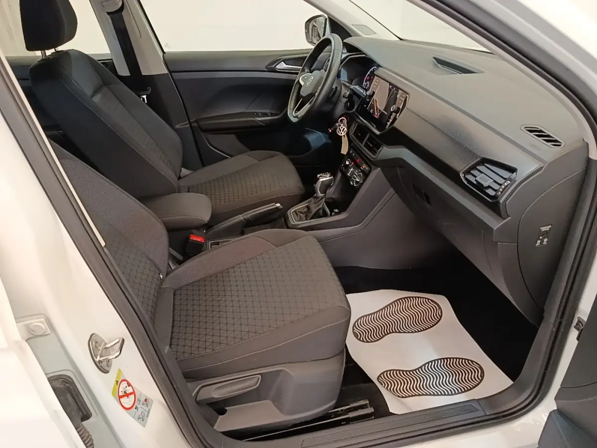 Vue intérieure côté conducteur du Volkswagen T-Cross blanc 2022, montrant sièges tissu noirs et tableau de bord moderne.