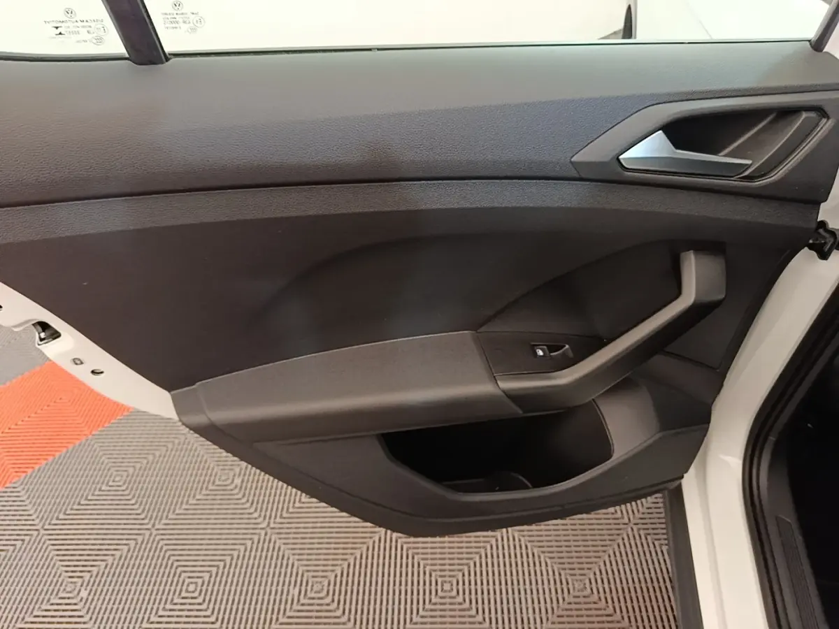 Vue intérieure de la porte avant droite noire du Volkswagen T-Cross blanc, avec poignée et bouton de lève-vitre.