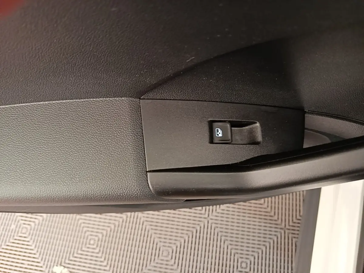 Gros plan sur la commande de verrouillage des portes intégrée à la portière côté conducteur d’un Volkswagen T-Cross blanc.