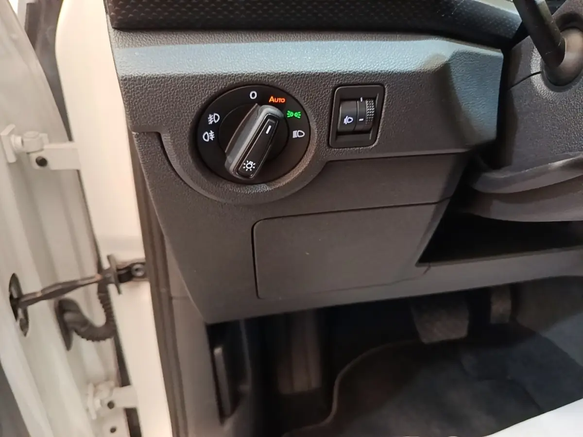 Détail du tableau de bord côté gauche du Volkswagen T-Cross blanc, avec commande d’éclairage et réglage des phares.