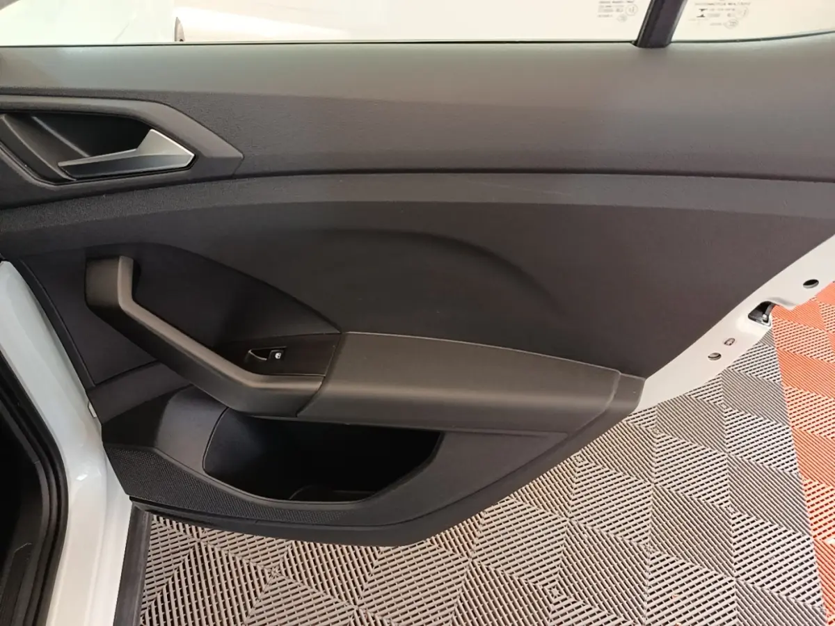 Intérieur côté gauche de la porte avant blanche du Volkswagen T-Cross 2022 avec poignée noire et bouton de vitre électrique.