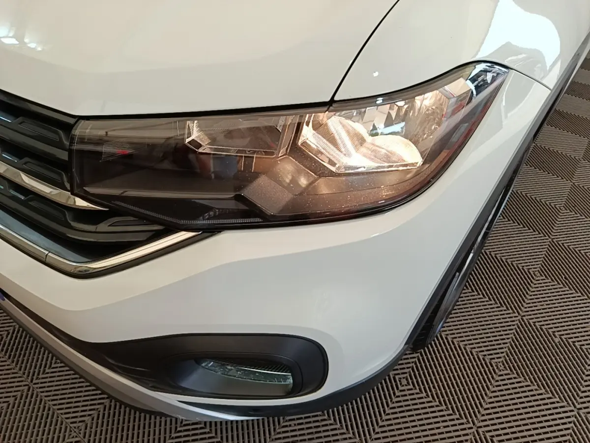 Gros plan sur le phare avant droit blanc du Volkswagen T-Cross 2022 avec antibrouillard et calandre noire.