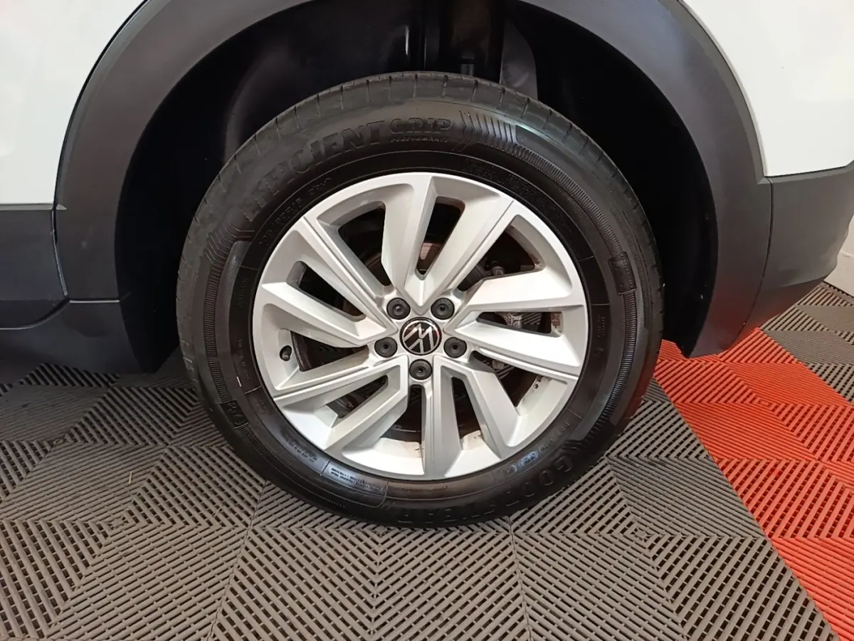 Gros plan sur la roue avant droite d’un Volkswagen T-Cross blanc, jante alliage à dix branches.