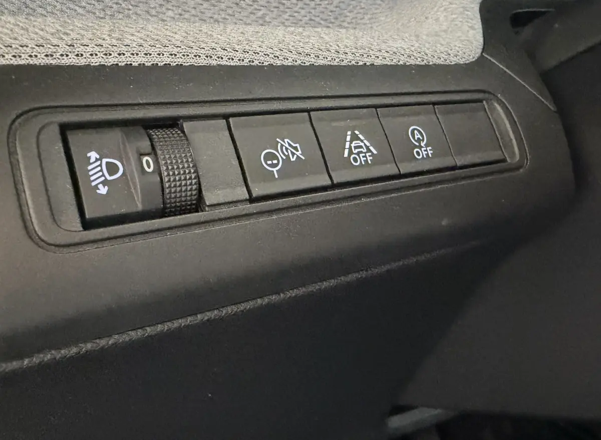 Gros plan sur les commandes de réglage des phares et aides à la conduite dans une Citroën C3 Turbo 100 BVM6 MAX noire.