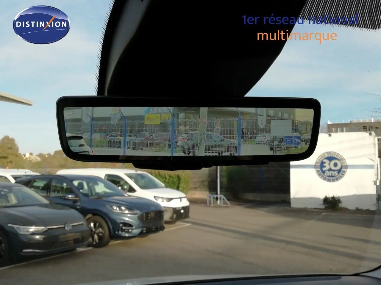 Vue intérieure centrée sur le rétroviseur, reflétant plusieurs véhicules dont un Citroën Berlingo blanc Icy en arrière-plan.