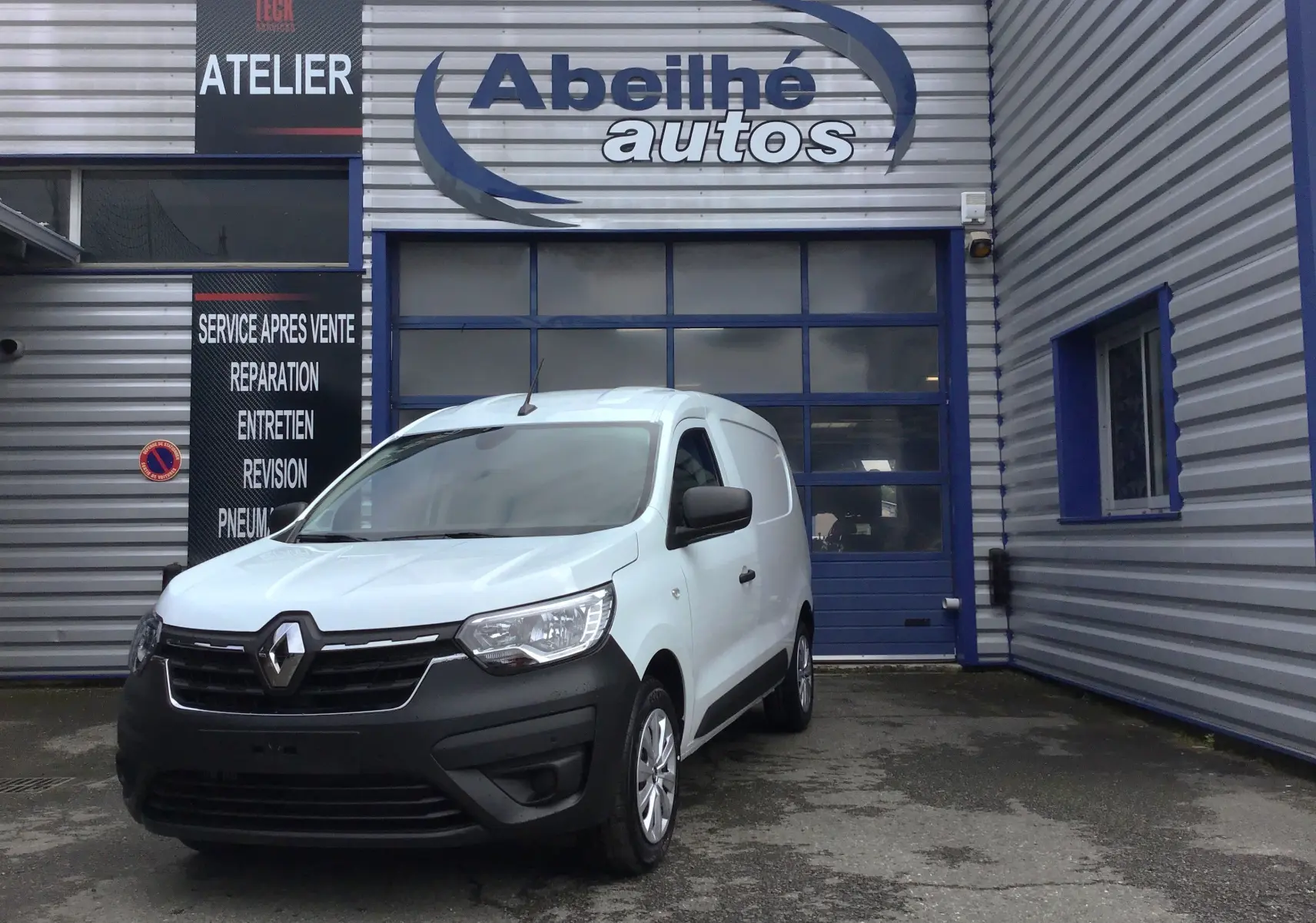 Renault Express Van blanc vu en 3/4 avant droit devant un garage avec enseigne Abeilhé autos.