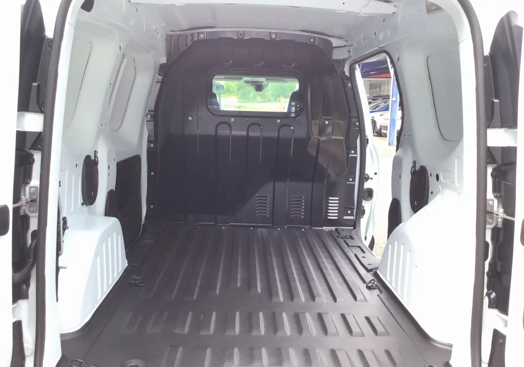 Vue intérieure arrière du Renault Express Van blanc 2024, montrant l'espace de chargement avec plancher PVC et cloison noire.