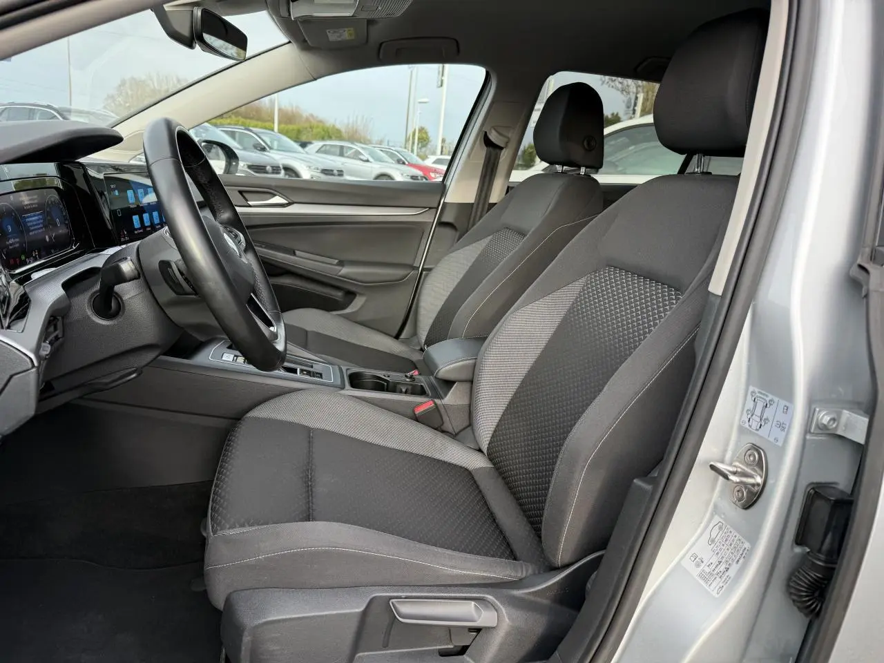 Intérieur avant droit d'une Volkswagen Golf 2022 argent métallisé, sièges tissu gris et tableau de bord moderne.