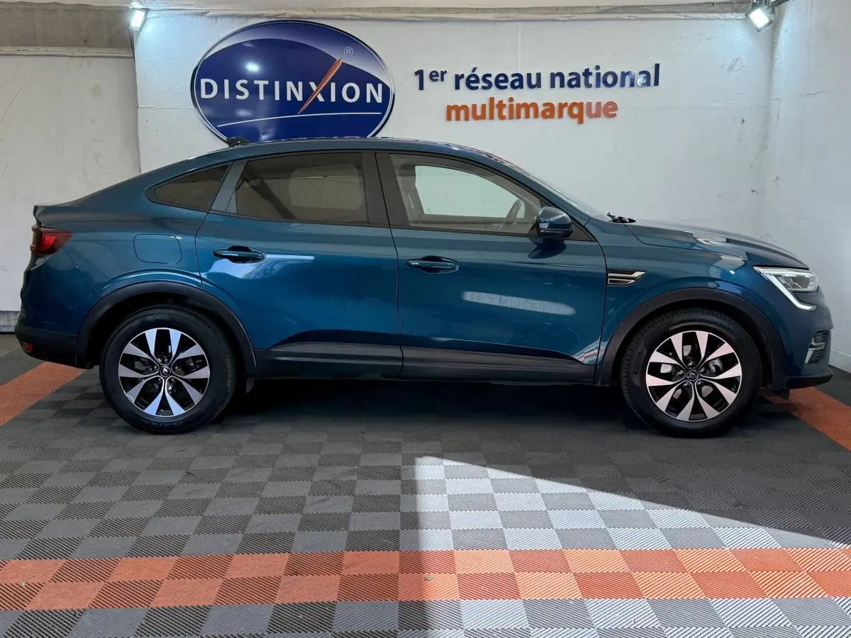 Profil latéral droit d'une Renault Arkana Business E-TECH 145 bleu, avec jantes alliage et lignes fluides.