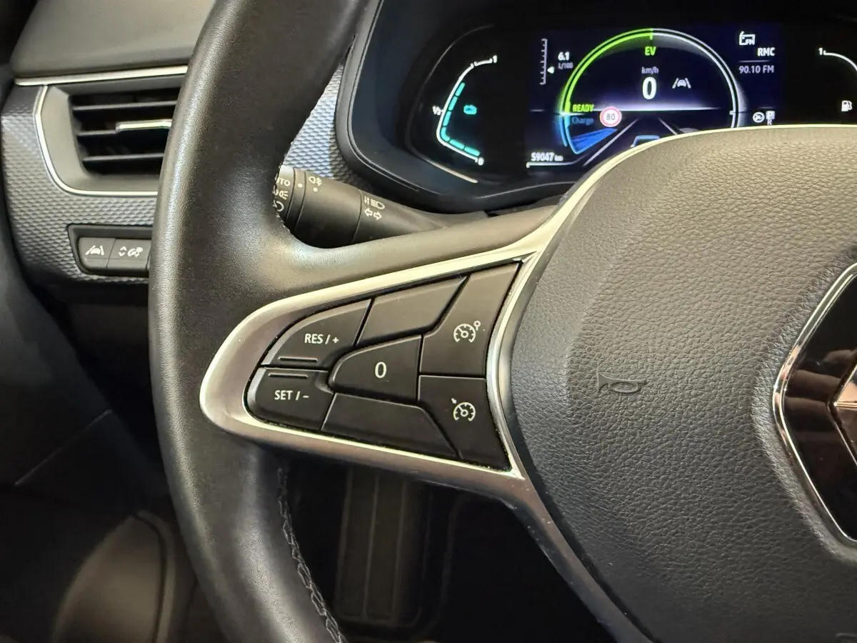 Gros plan sur le volant cuir et alu de la Renault Arkana Business E-TECH 145 avec tableau de bord numérique allumé.